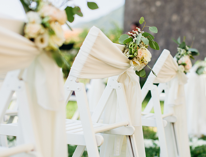 Wedding chairs with white sashes and flowers for a reception at the Catamaran Resort