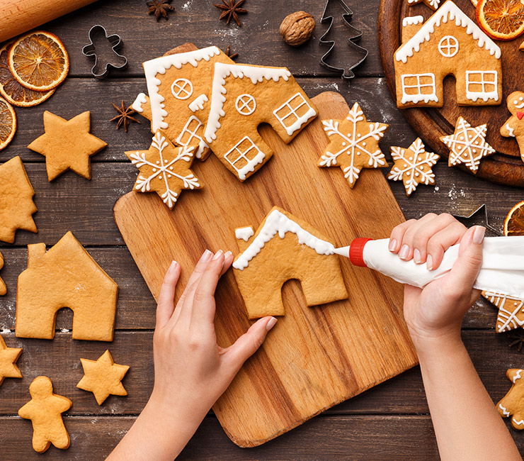 Hands making and decorating a ginger bread house