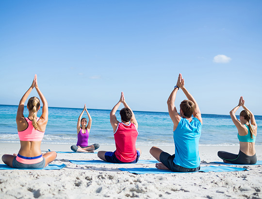 Group of adults doing yoga on the beach