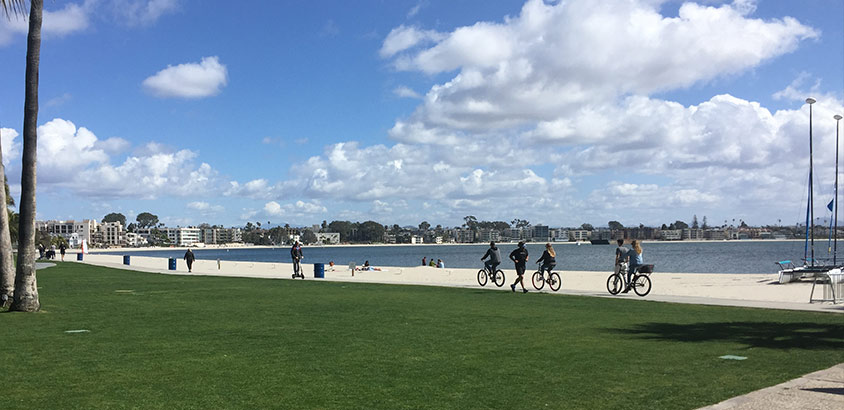 Local San Diegans and Tourists exercising on the Mission Bay boardwalk in front of the Catamaran Resort Hotel by Pacific Beach, San Diego, CA.