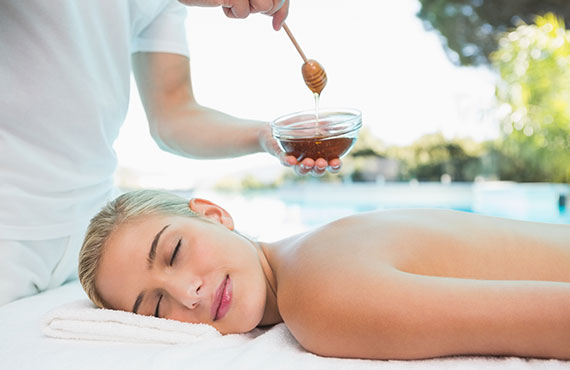 Side view of an attractive young woman receiving spa treatment with honey
