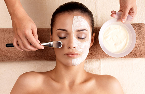 Spa therapy for young woman receiving facial mask at beauty salon