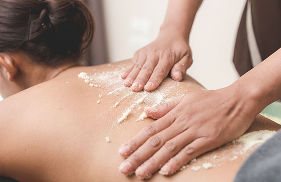 woman njoying a scrub massage and having exfoliation treatment in spa room