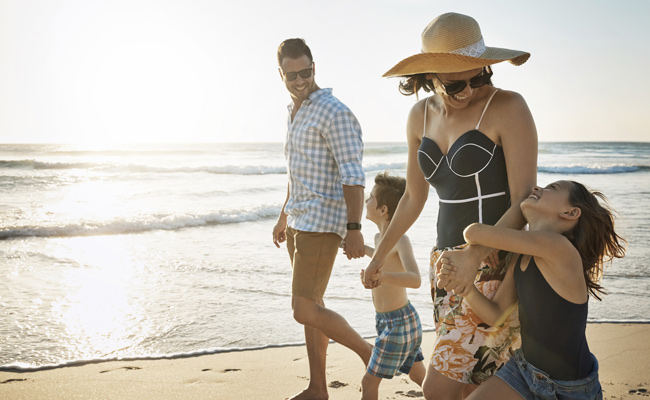 Family taking a stroll on the beach at sunset on their workation at the Catamaran Resort Hotel