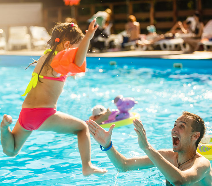 Girl jumping into pool into parents arms