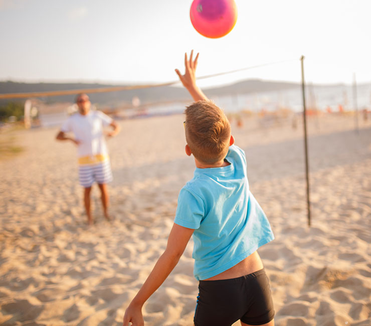 A family playing beach volleyball at the Catamaran Resort Hotel beach on the shores of Mission Bay in San Diego, CA.