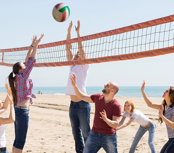 Adults playing volleyball on the beach during team building activities in San Diego at the Catamaran Resort Hotel.