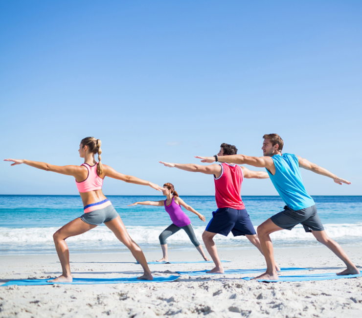 Group of adults doing yoga on the beach