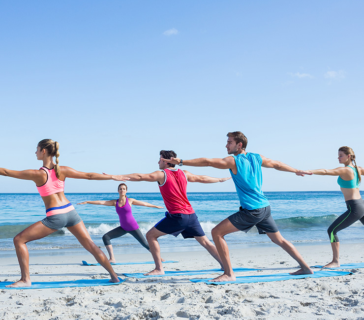 Co-workers experiencing yoga on the beach, one of the many team building activities at the Catamaran Resort Hotel in San Diego.