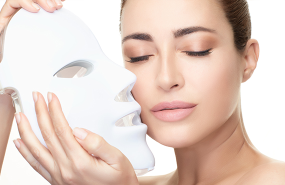 Woman holding LED facial mask.