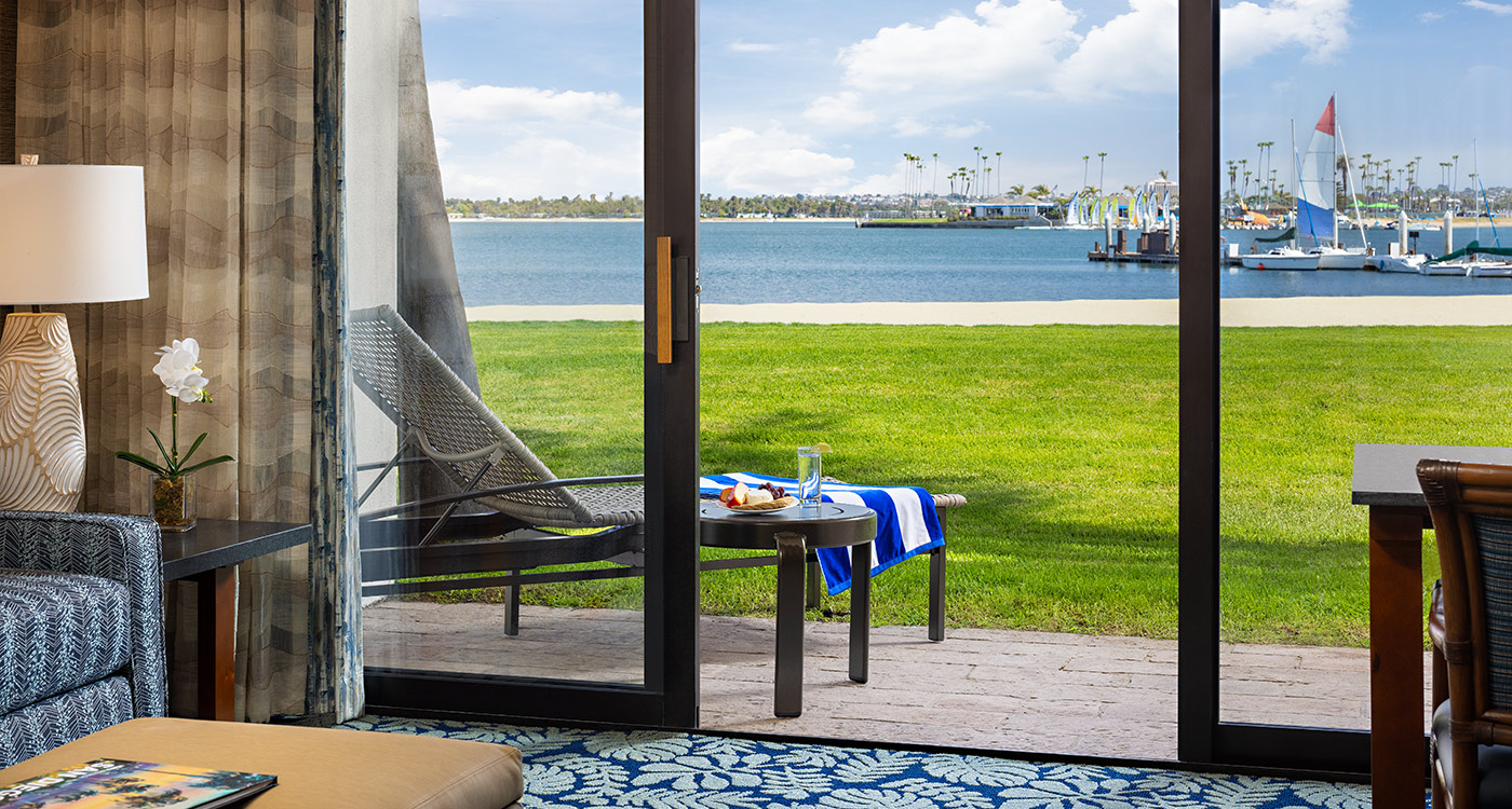 A room with a sliding glass door leading to a patio overlooking the water.