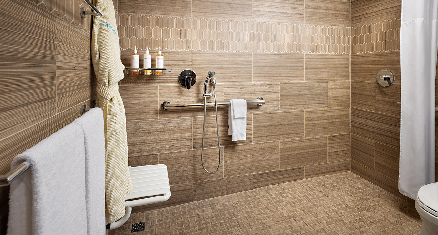 A bathroom with a roll-in shower, grab bar, and seat