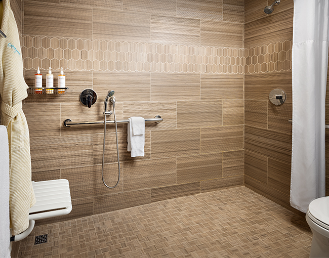 A bathroom shower with tiled walls, a shower curtain, and a toilet in the background.