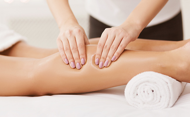 Masseuse massaging a guest's calf for a Deep Tissue Massage at the Catamaran Spa