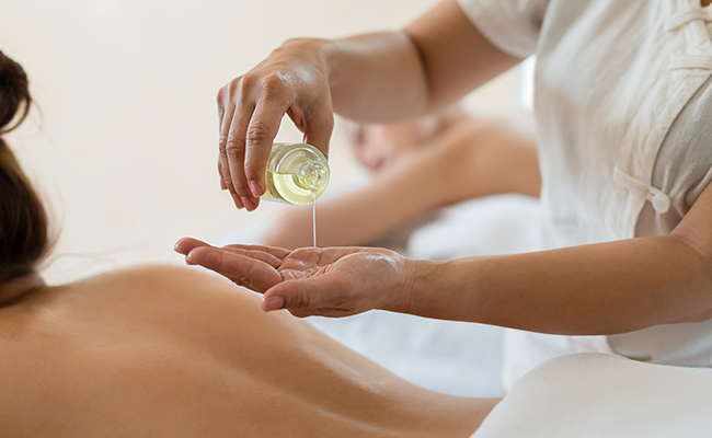 Masseuse pouring oil in preparation to perform a Restorative CBD Massage at the Catamaran Spa