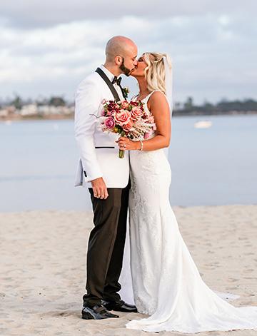 Bride and groom, Jordan and Derrace share a kiss at their beach wedding on the shores of Mission Bay at the Catamaran Resort Hotel and Spa in San Diego.