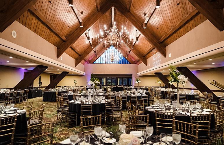 A classic wedding reception with black and white linens in the Kon Tiki Ballroom at the Catamaran Resort Hotel in San Diego.